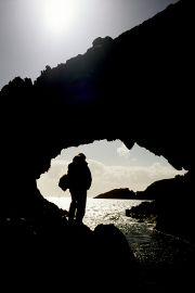 A walker stands in silhouette in a rock arch on Cape Clear Island.